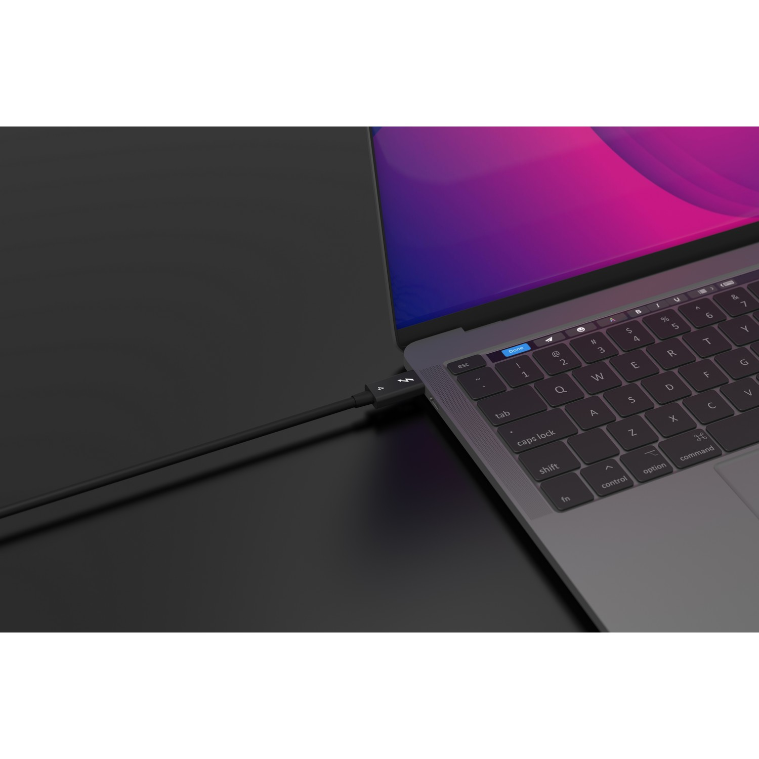 Un câble noir connecté à un ordinateur portable sur une surface sombre.