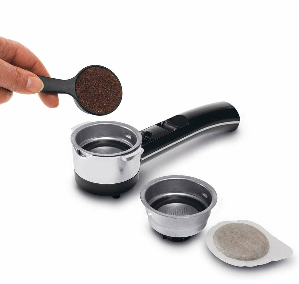 Dłoń trzymająca zmieloną kawę, kolba z koszami i saszetką kawy, białe tło.