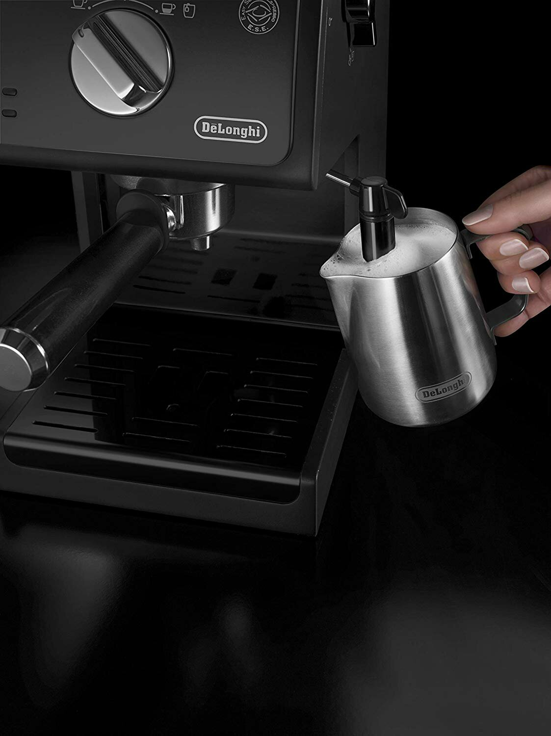 Czarny ekspres do espresso Delonghi z ręką wlewającą piankę mleczną do dzbanka ze stali nierdzewnej.