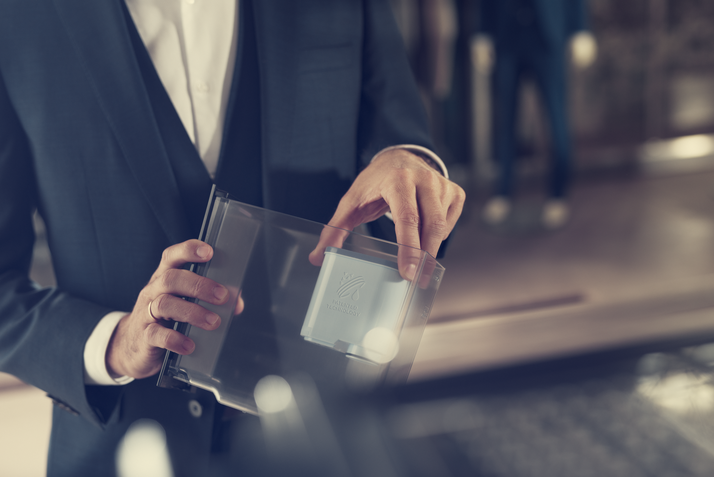 Osoba trzymająca przezroczystą tacę z kartą w środku. Karta ma logo.