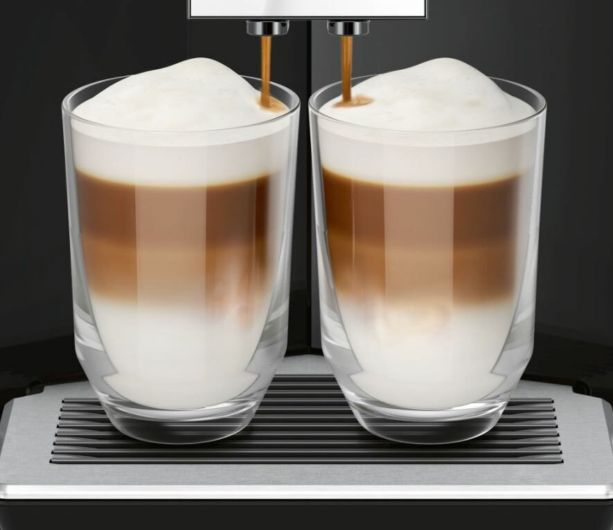 Zbliżenie na dwa szklanki latte podczas nalewania.