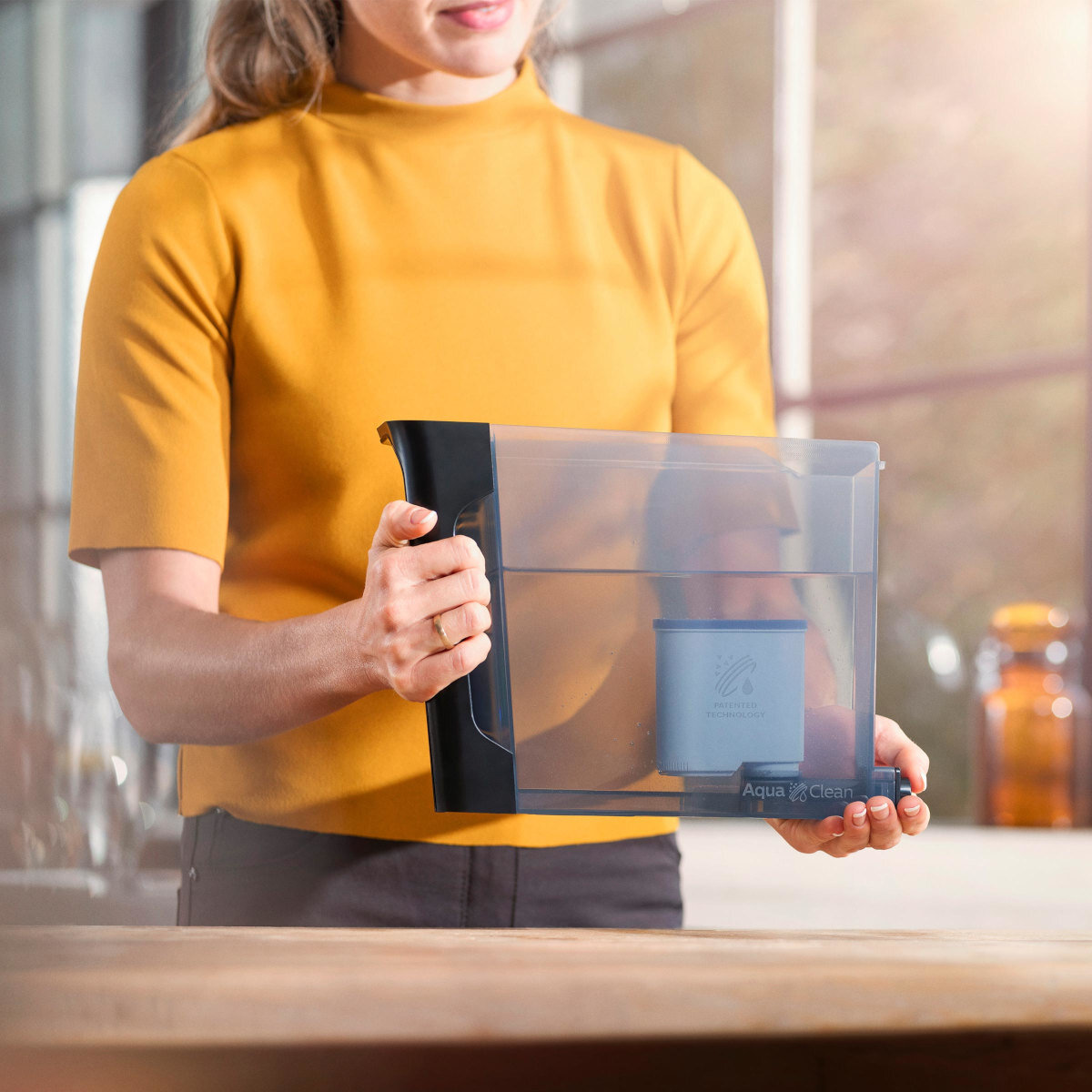 Osoba trzymająca dzbanek z filtrem do wody. Dzbanek jest przezroczysty z niebieskim filtrem.