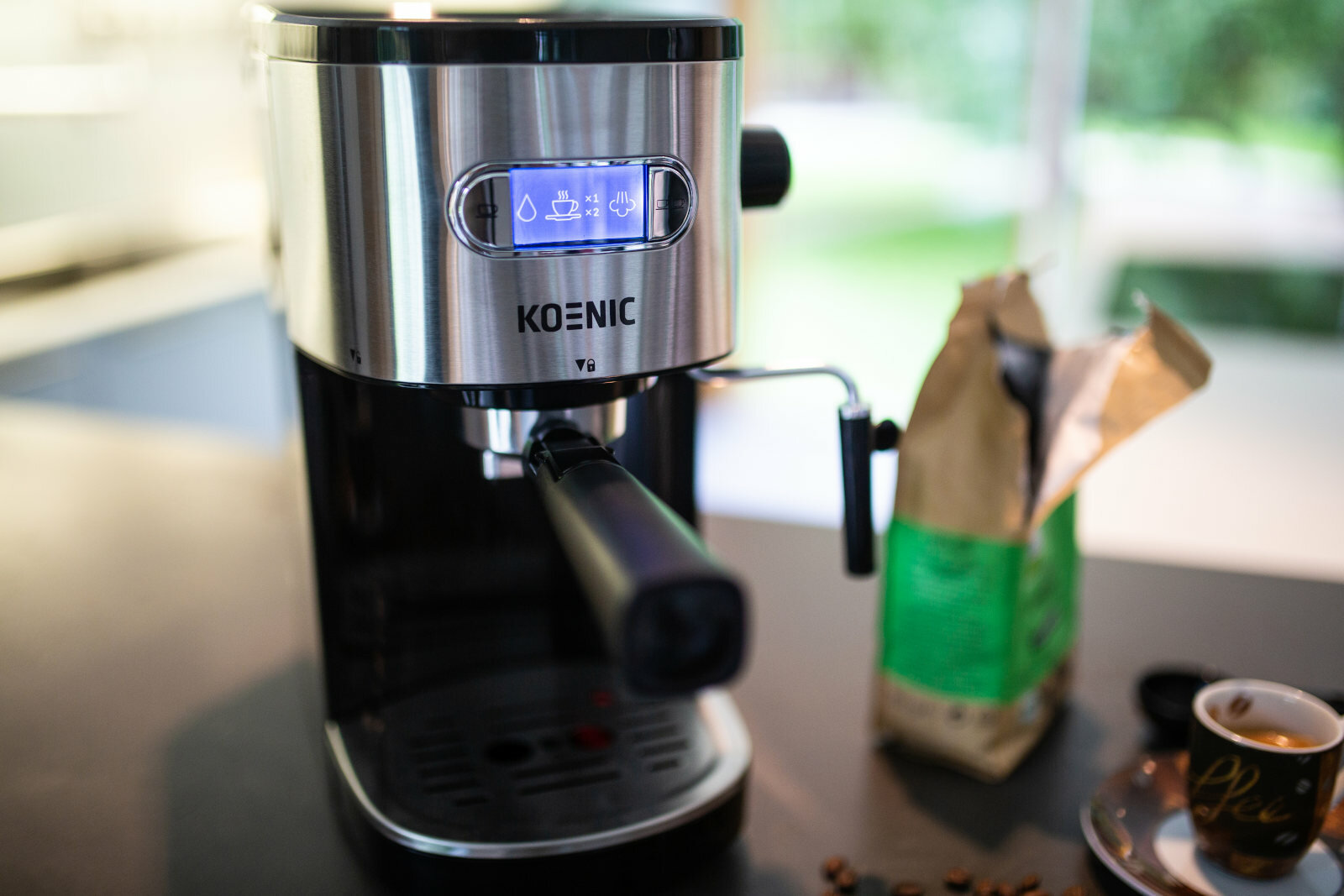 Ekspres do kawy na blacie z workiem ziaren kawy i filiżanką.