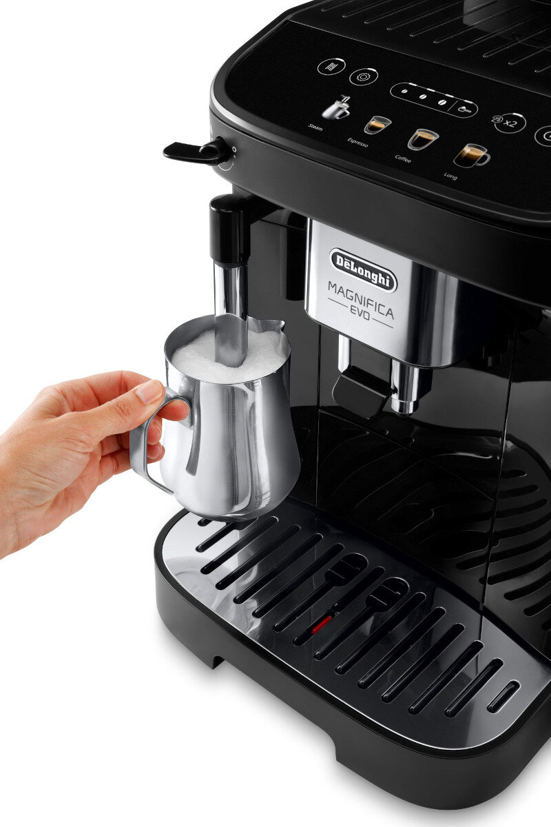 Czarny ekspres do kawy Delonghi Magnifica EVO z ręką trzymającą srebrny dzbanek na mleko.