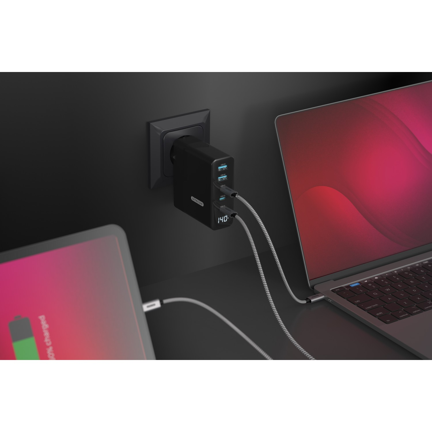 Een zwart oplaadblok met meerdere poorten is aangesloten op een stopcontact en laadt een tablet en een laptop op.