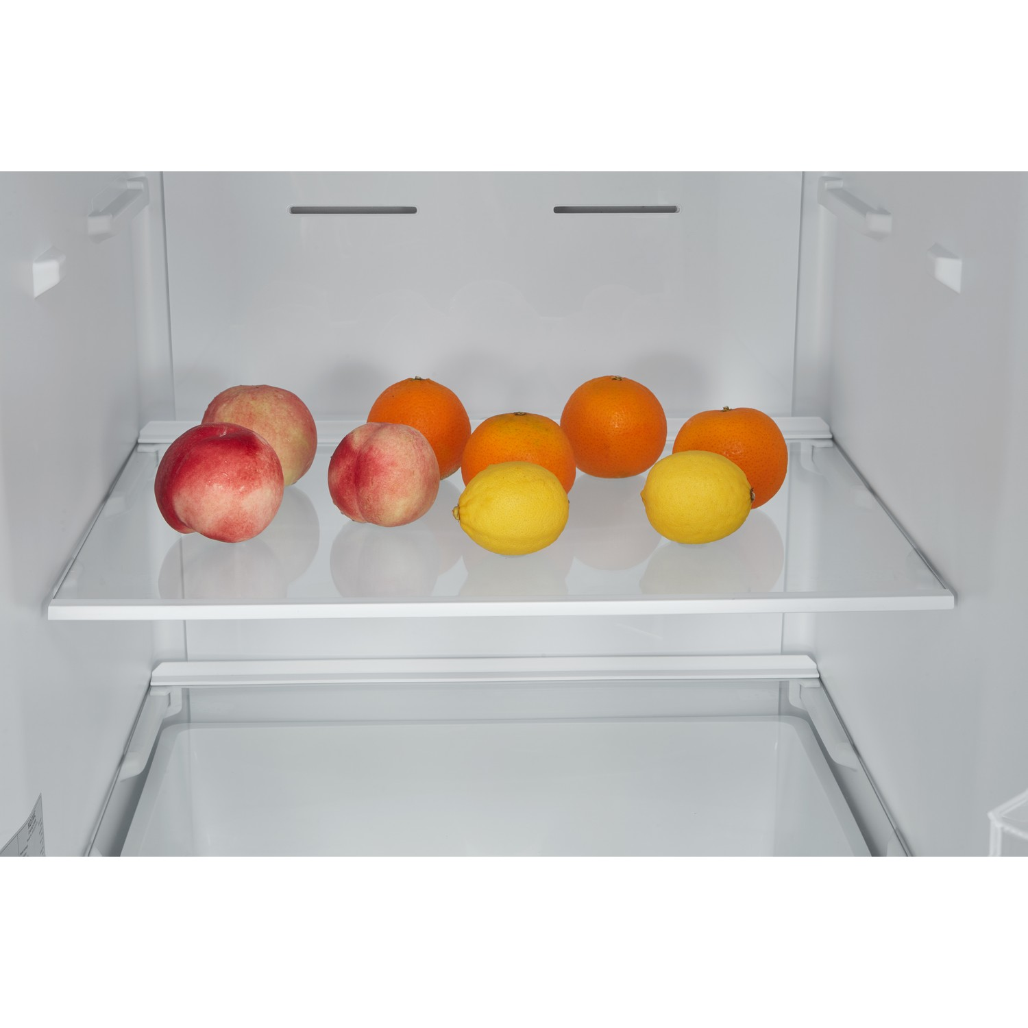 Open refrigerator with peaches, oranges, and lemons on shelves.