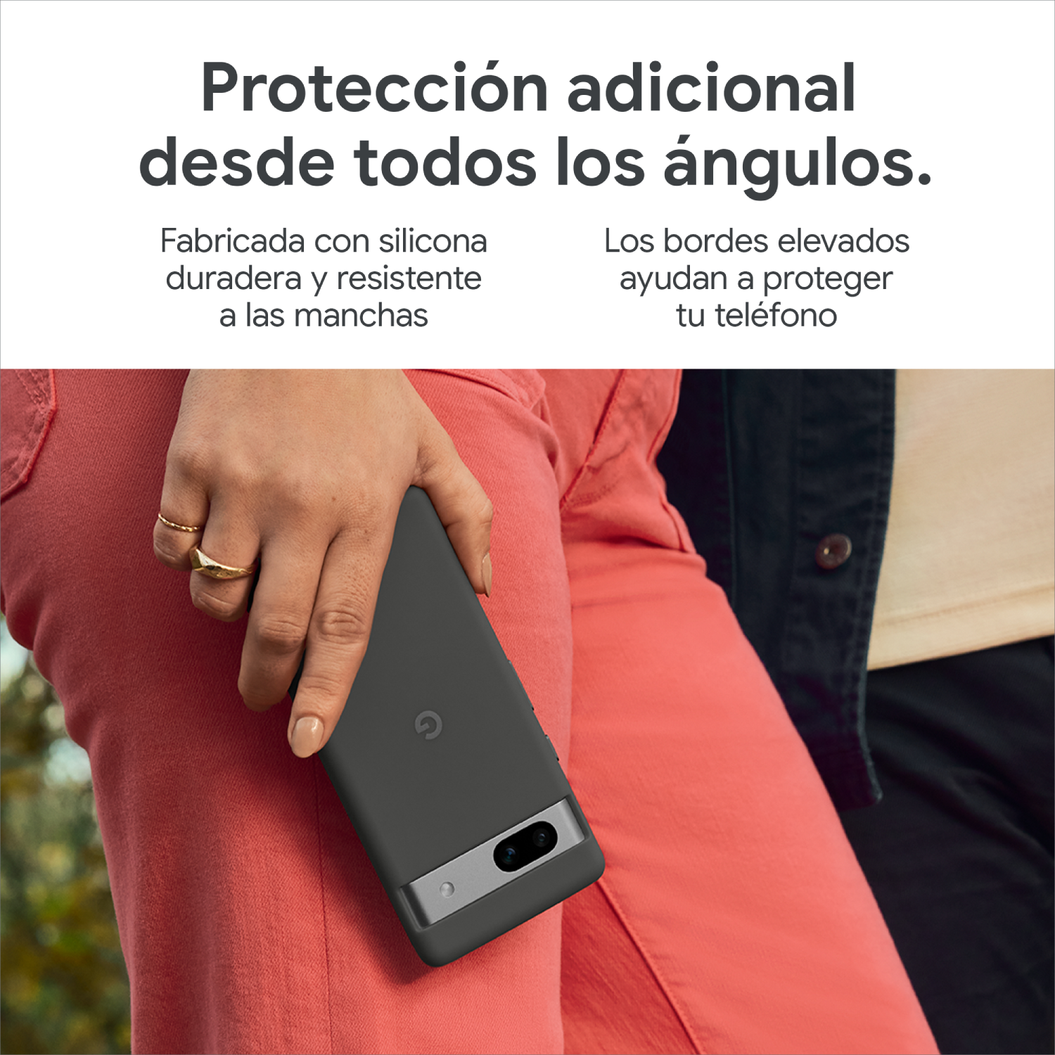 Persona sosteniendo un teléfono gris con funda gris, pantalón rojo, fondo blanco.