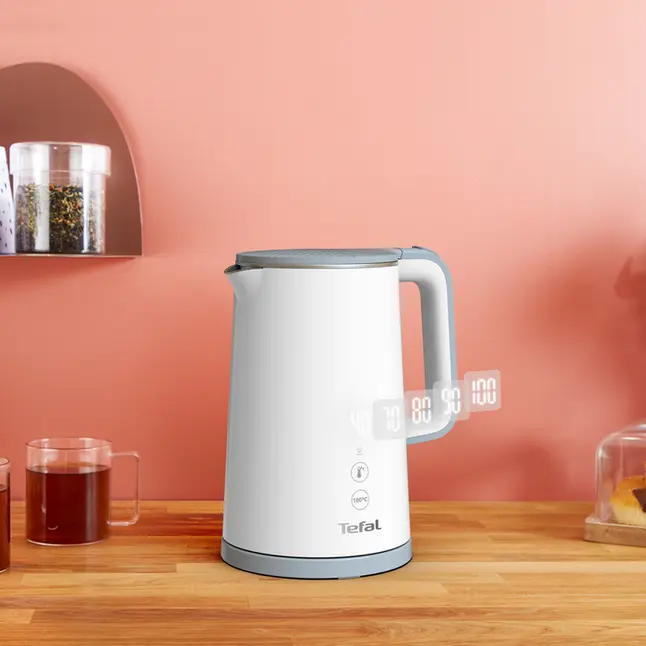 Biały i szary czajnik elektryczny z wyświetlaczem cyfrowym pokazującym poziomy temperatury na drewnianym stole.