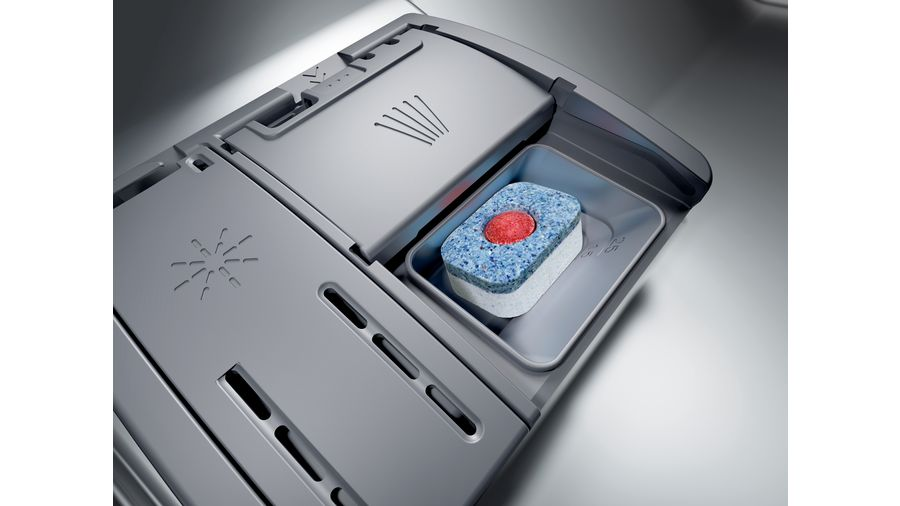 Dispensador de detergente de lavavajillas con una pastilla azul y roja dentro, y otros compartimentos.