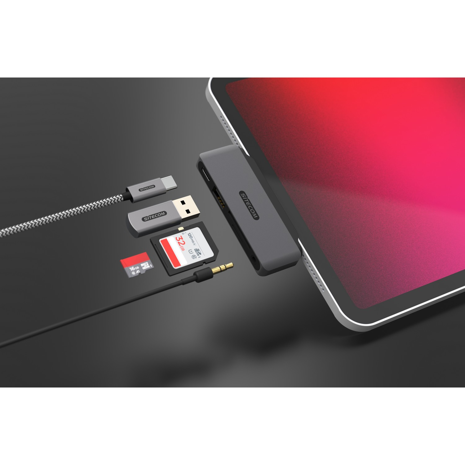 Un iPad avec un hub connecté, USB, carte SD et prise audio sur une surface sombre.