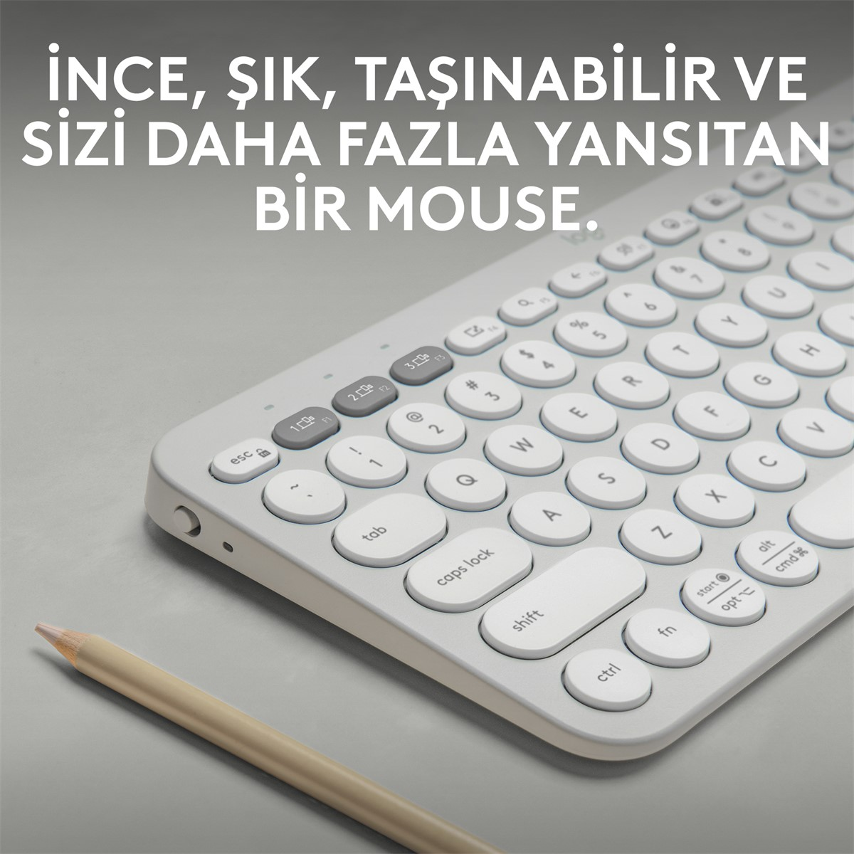 Beyaz yuvarlak tuşlu kablosuz klavye ve yanında bir kurşun kalem.