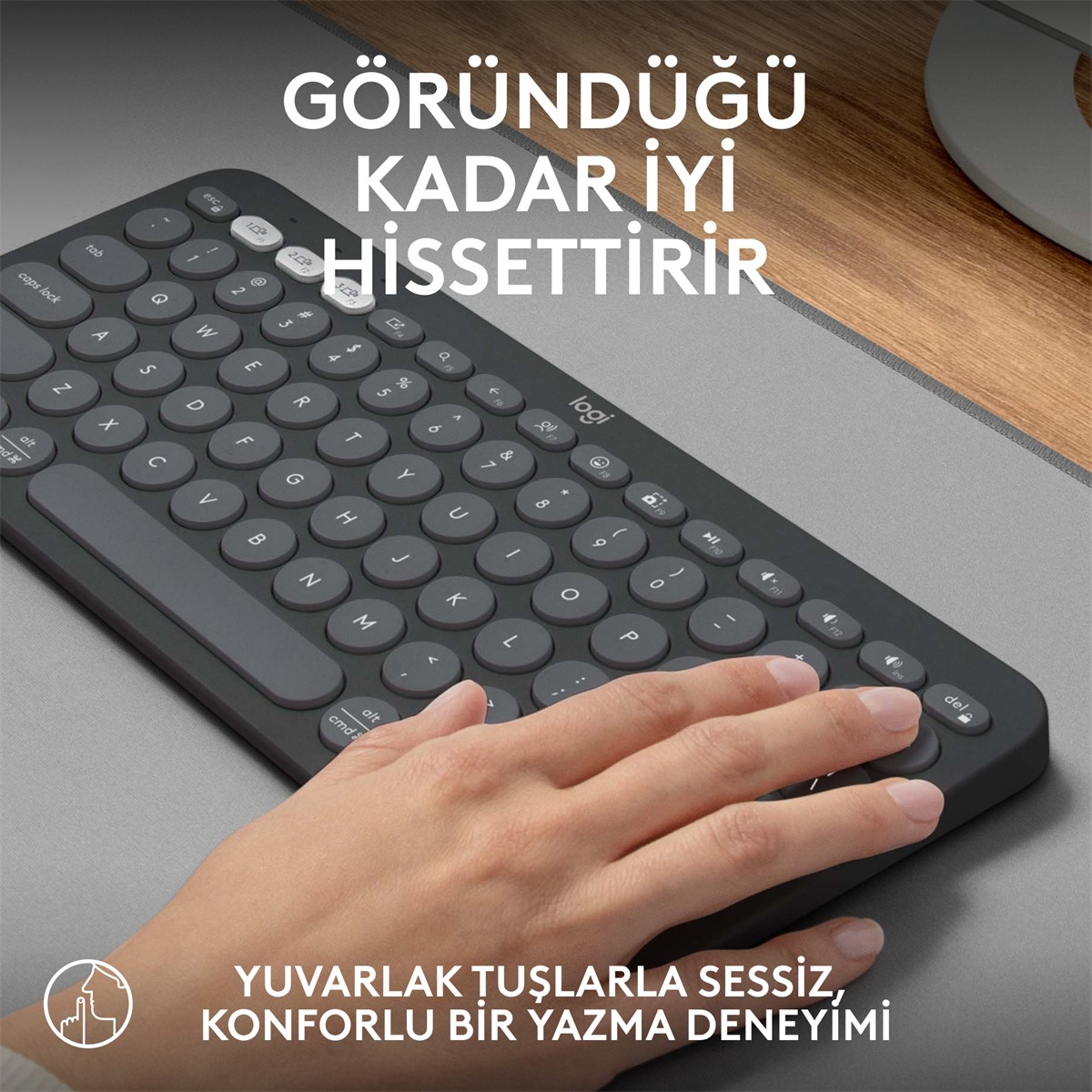 Kullanılan bir elle koyu gri klavye. Tuşlar koyu gri ve yuvarlak şekillidir.
