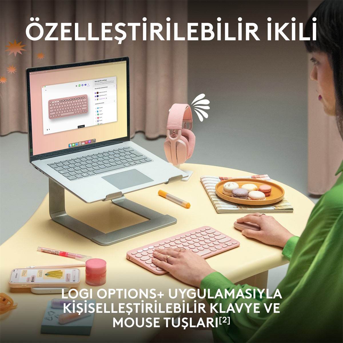 Kadın bir masada dizüstü bilgisayar, klavye ve kulaklıkla çalışıyor.