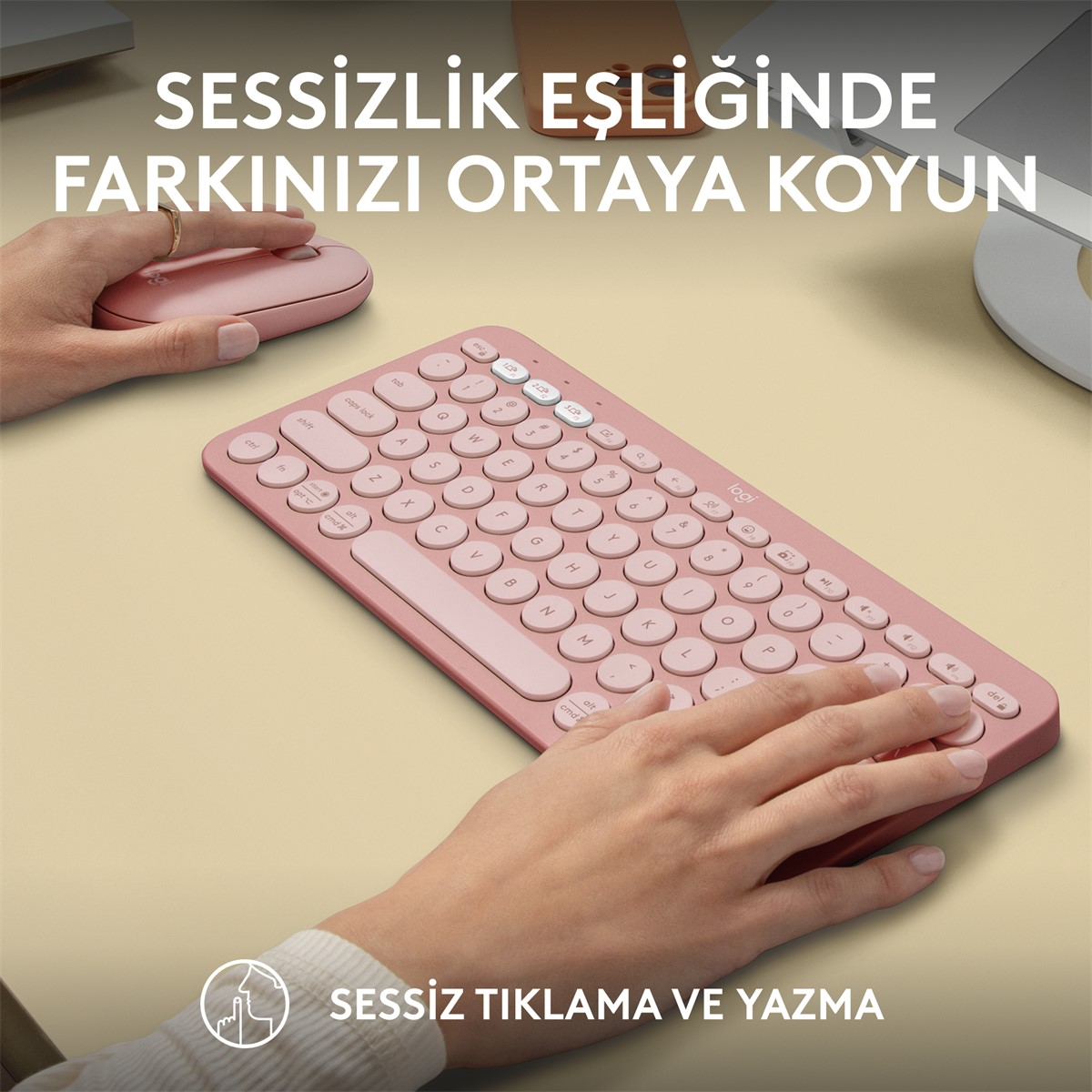 Pembe klavye ve fare masada, eller yazıyor ve tıklıyor.