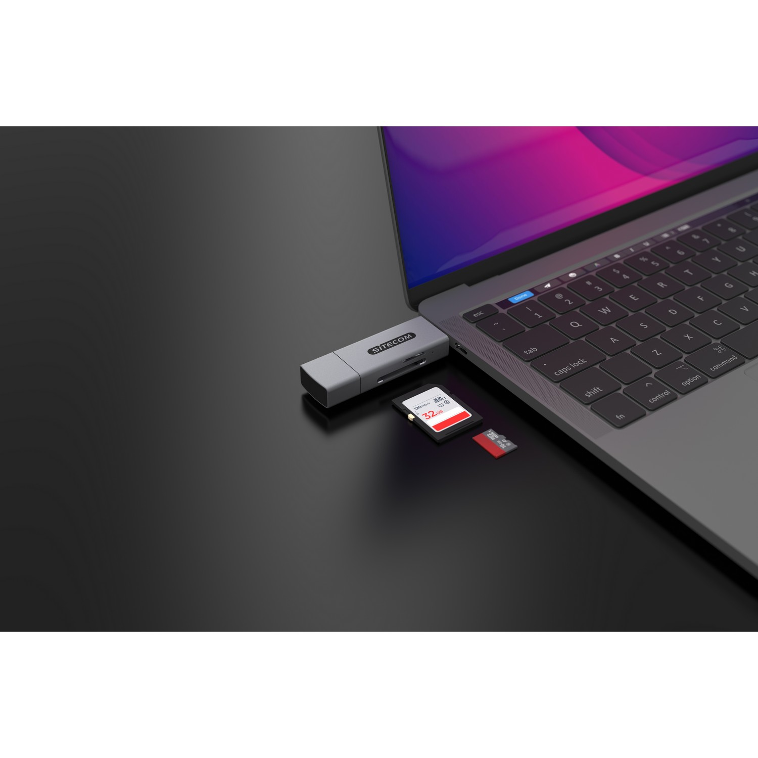A laptop connected to a silver adapter with a USB and a SD card.