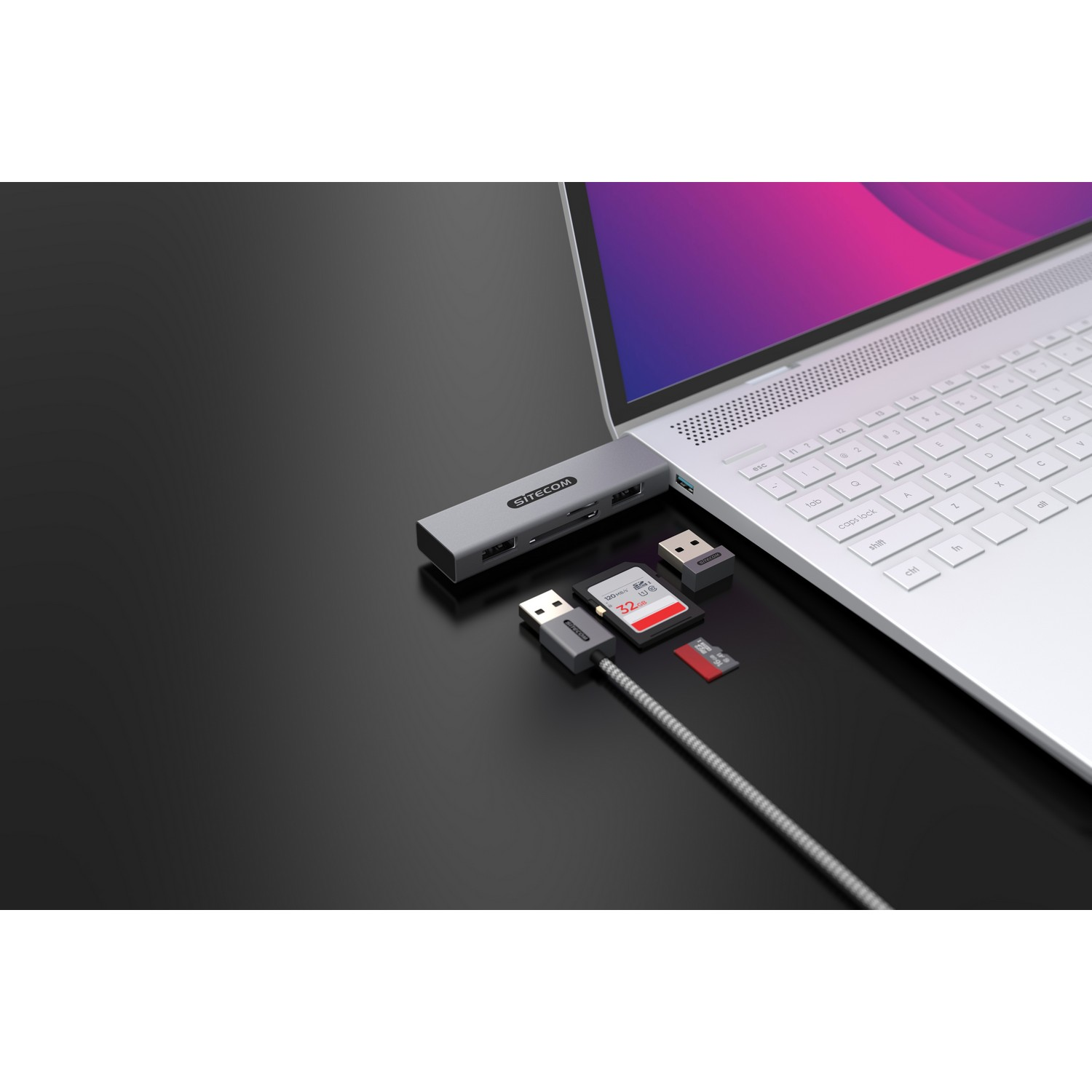 Silver USB-C hub connected to a laptop with various ports and connected devices. Includes SD cards.