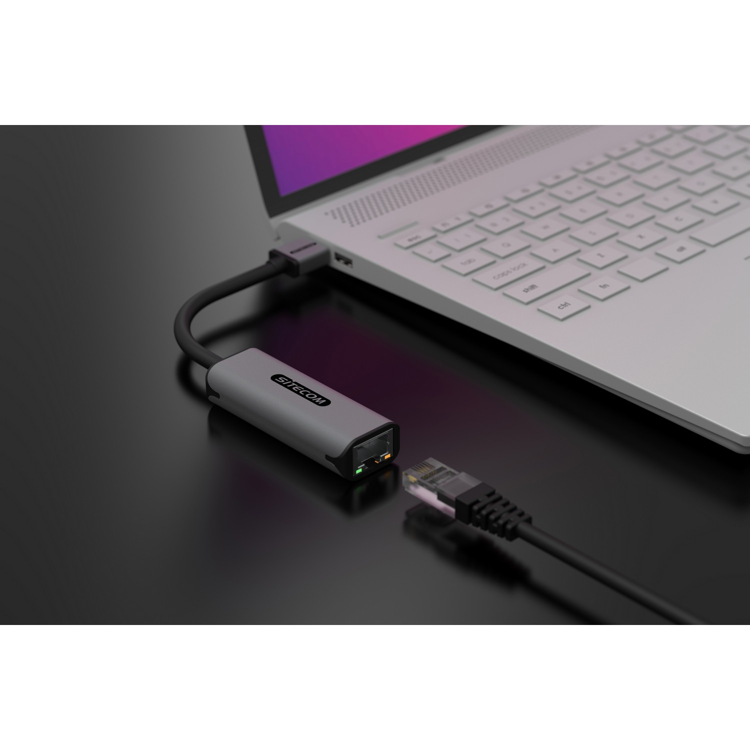 Ordinateur portable connecté à un adaptateur gris via un câble noir. Câble Ethernet branché.