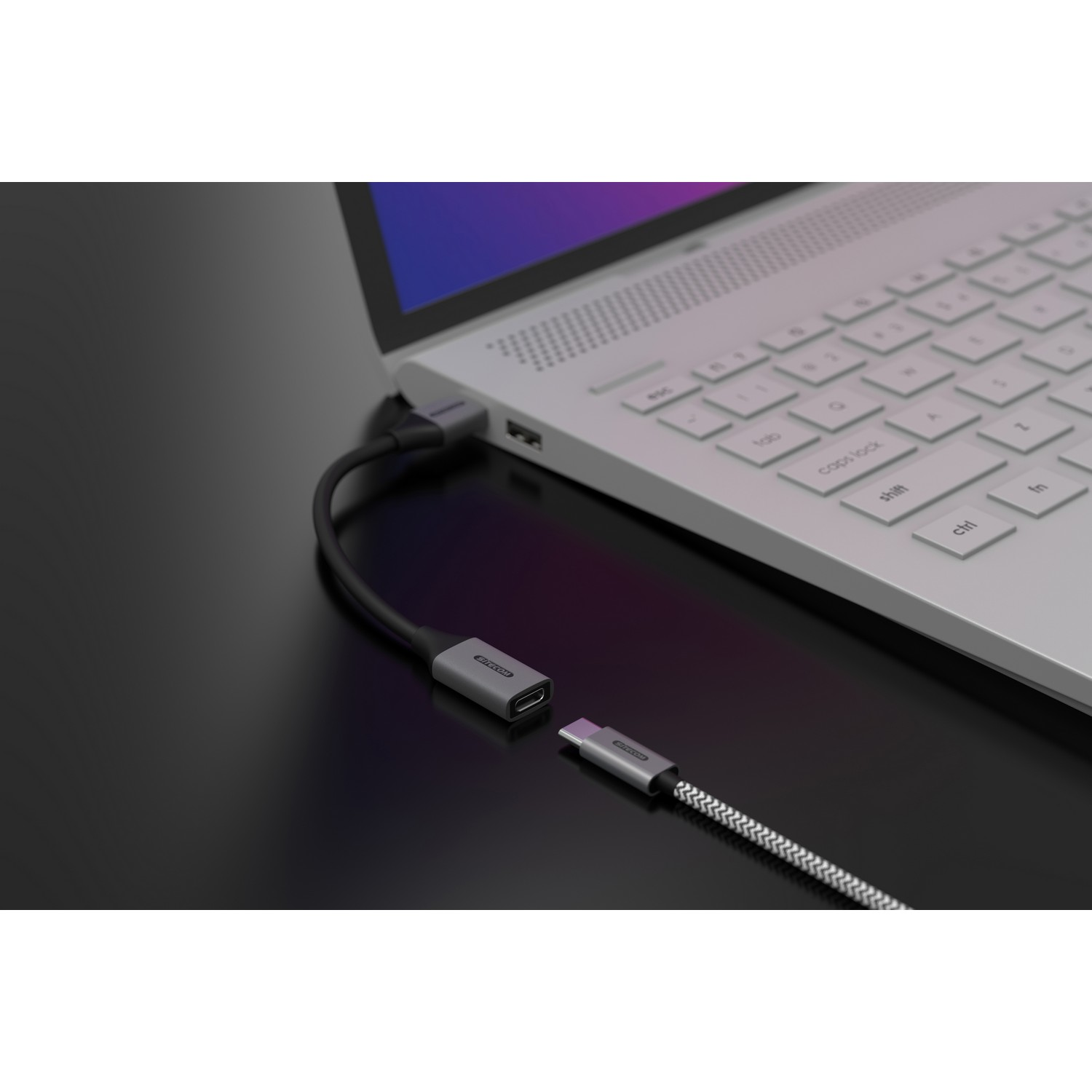 Un ordinateur portable est connecté à un câble USB-C, branché sur un adaptateur USB-C.