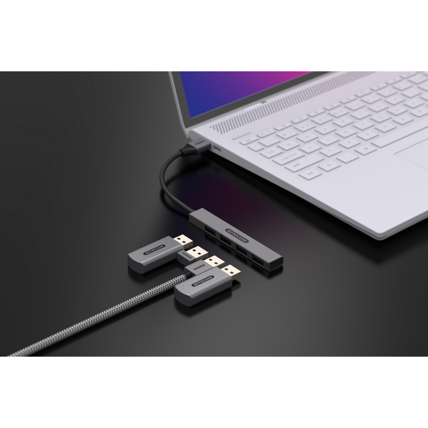 Ordinateur portable connecté à un hub et câbles HDMI sur une surface noire.
