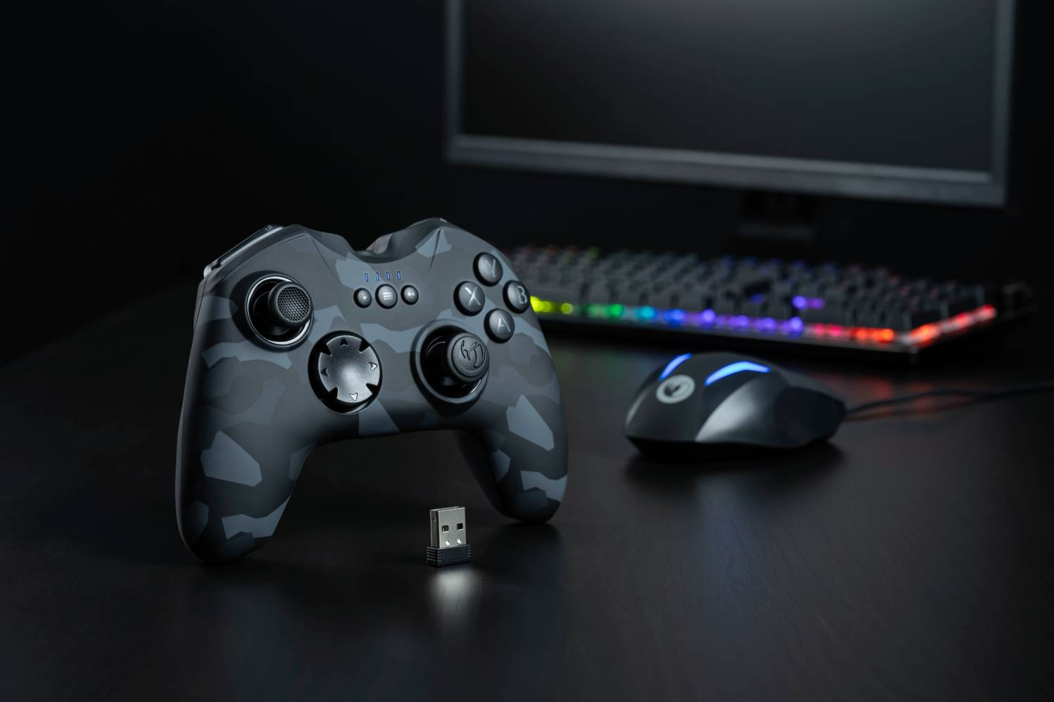 Un mando de juegos, un receptor USB inalámbrico, un ratón y un teclado están sobre un escritorio.
