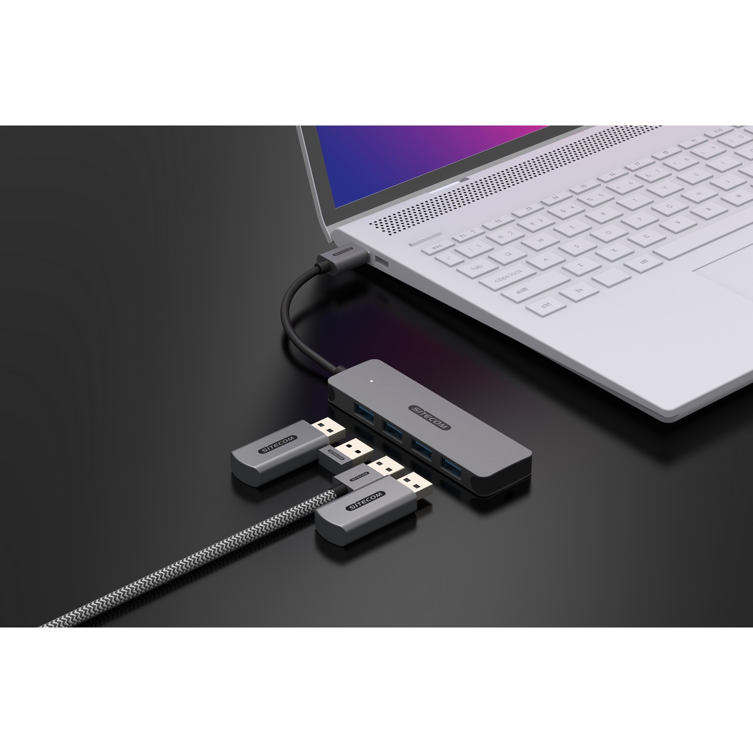 Un ordinateur portable connecté à un hub gris avec des ports USB. Plusieurs adaptateurs USB sont connectés.