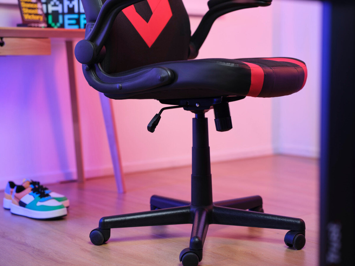Krzesło gamingowe z czerwonymi akcentami na drewnianej podłodze, z butami.