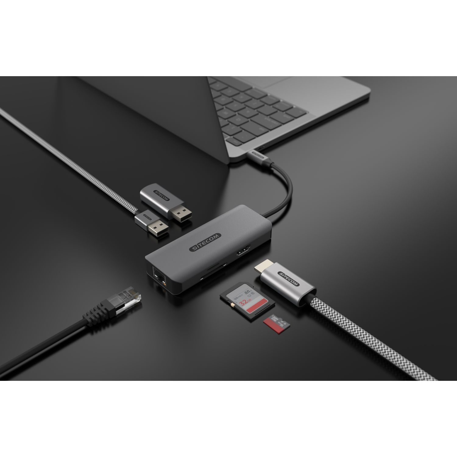 Un hub gris avec plusieurs ports, connecté à un ordinateur portable. Divers accessoires l'entourent.