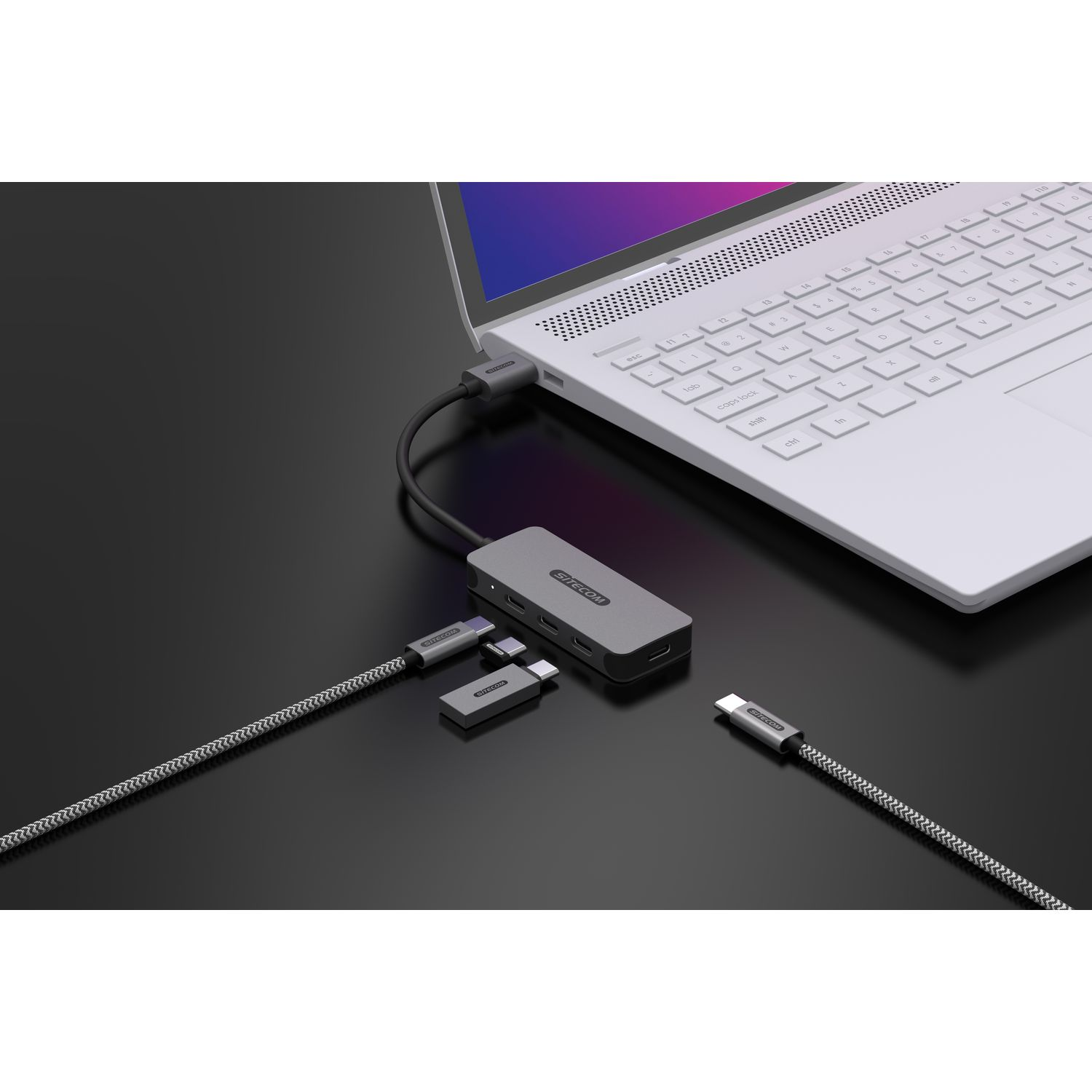 Un ordinateur portable connecté à un hub gris avec plusieurs câbles. Plusieurs connecteurs USB-C sont présents.