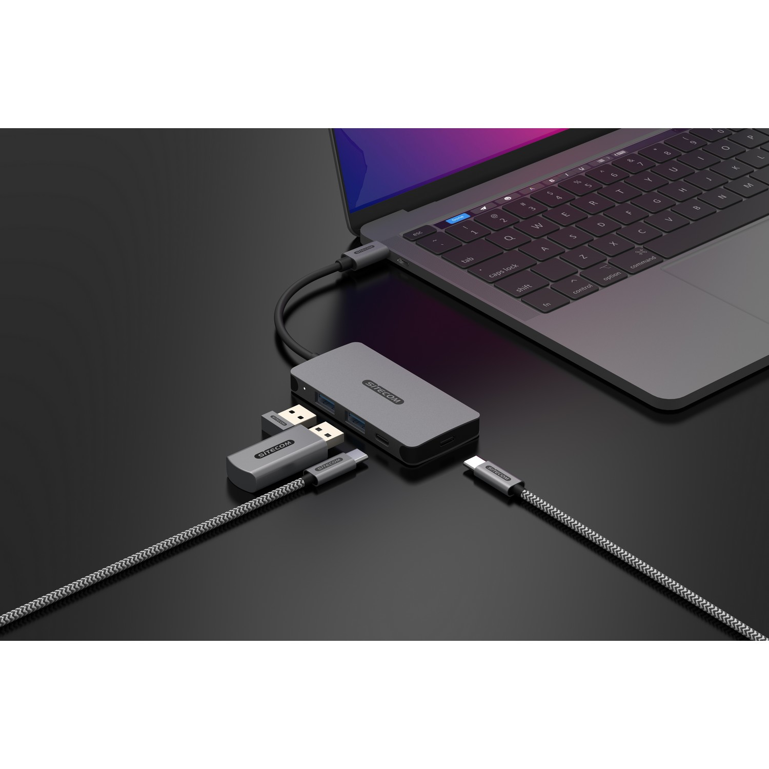 Ordinateur portable connecté à un adaptateur multiport et à d'autres appareils. La configuration est sur une surface sombre.