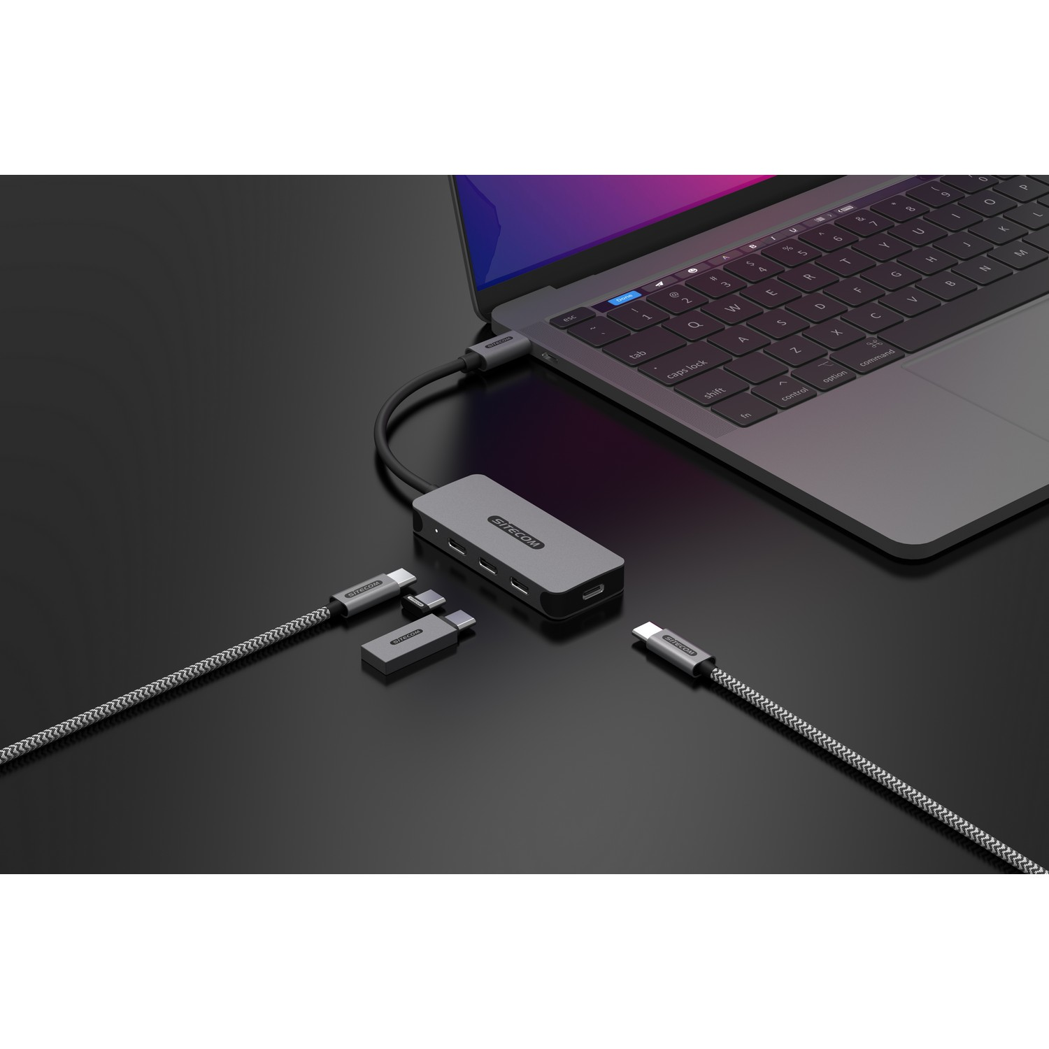 Ordinateur portable connecté à un hub gris avec divers câbles attachés.