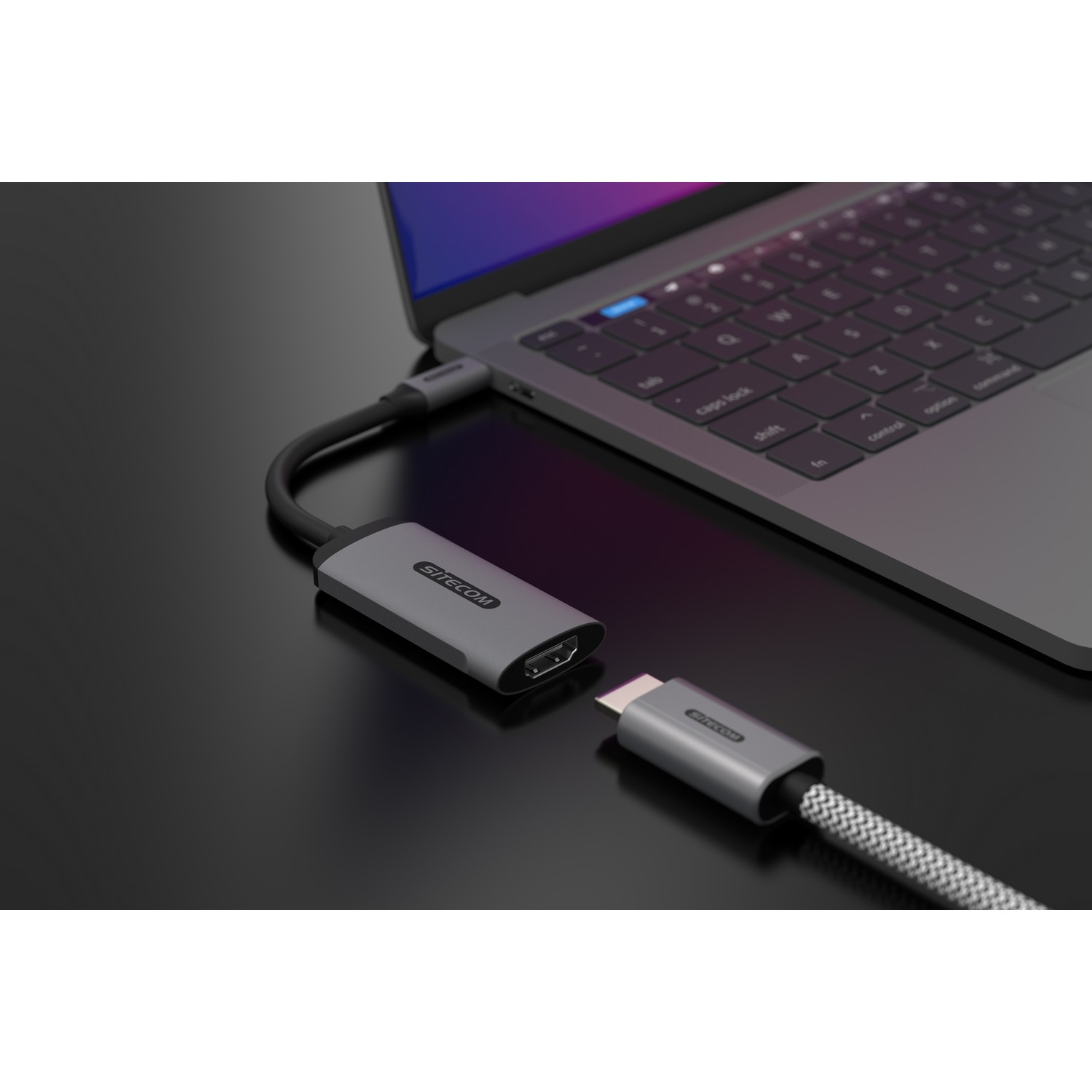 Laptop connected to a USB-C to HDMI adapter; adapter is grey and connected to a screen.