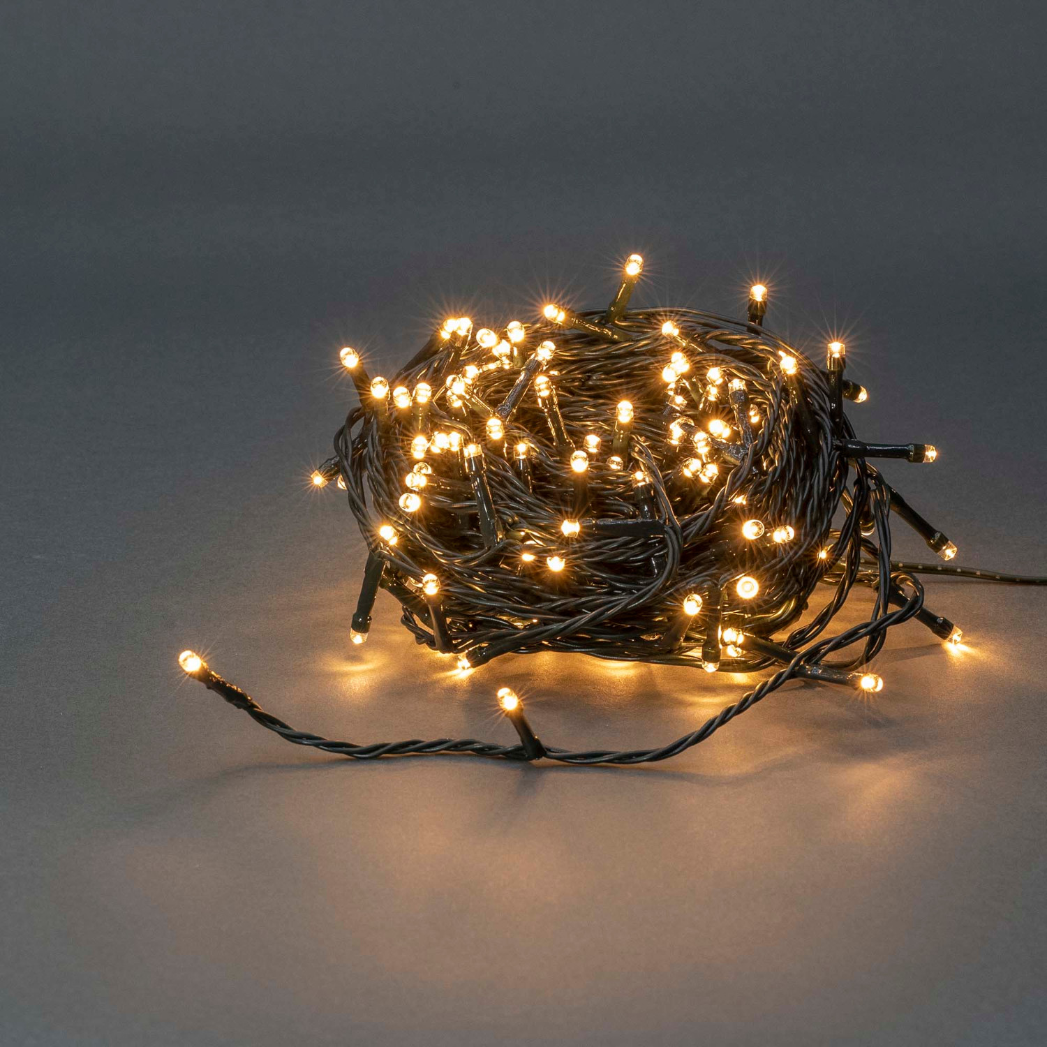 Een kluwen kerstverlichting met veel kleine, felgele lampjes op donkere draad.