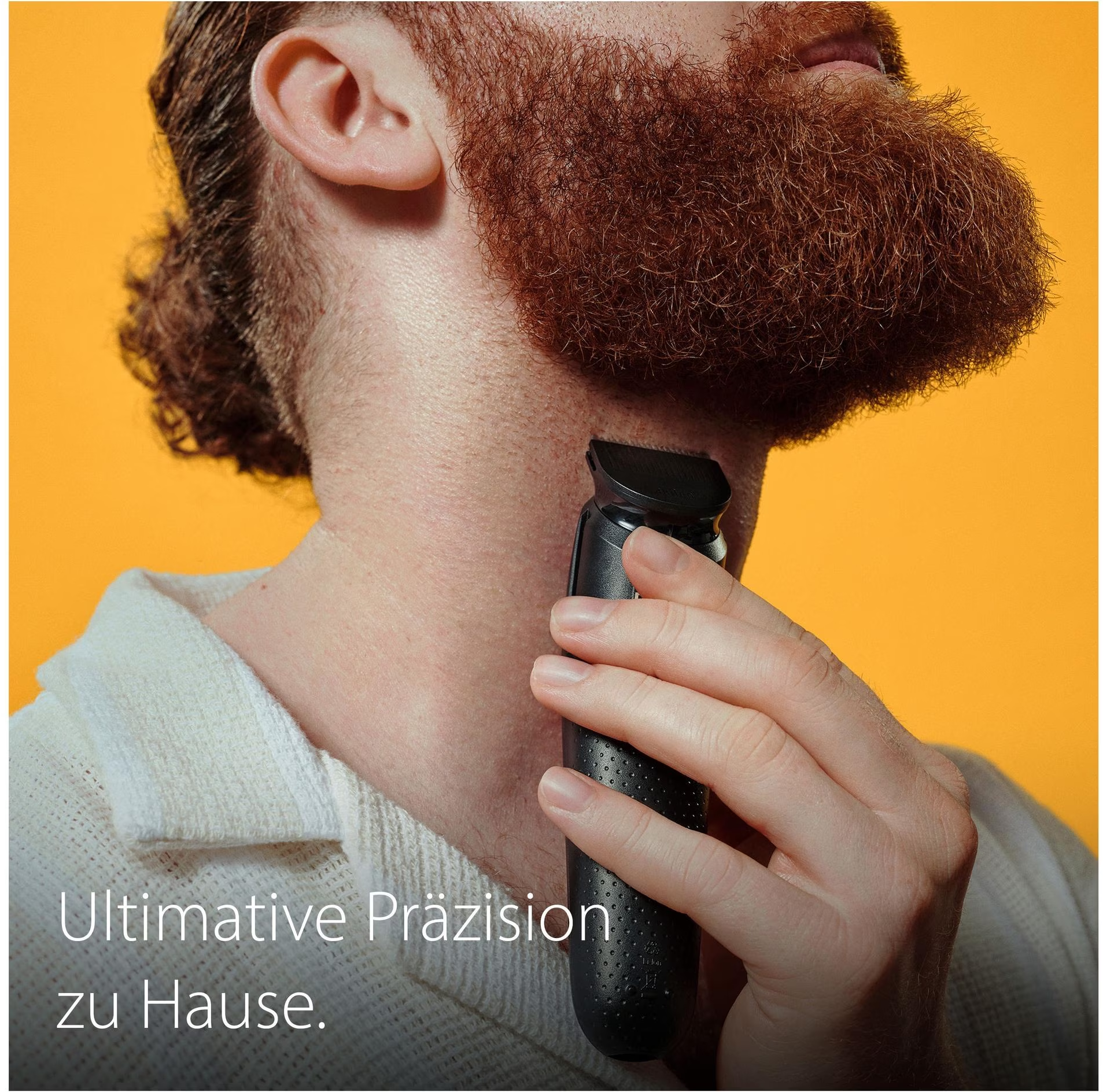 Ein Mann rasiert seinen Bart mit einem schwarzen Trimmer. Der Hintergrund ist gelb.