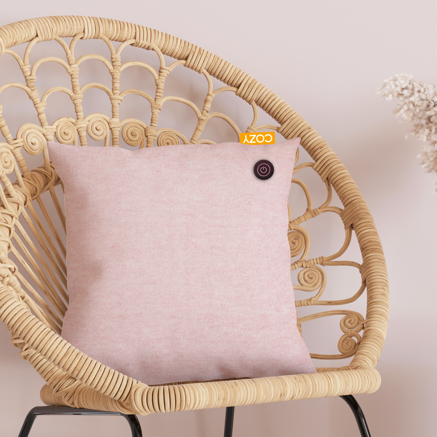 Pink heated cushion on a wicker chair. It has a black power button and a Cozy label.