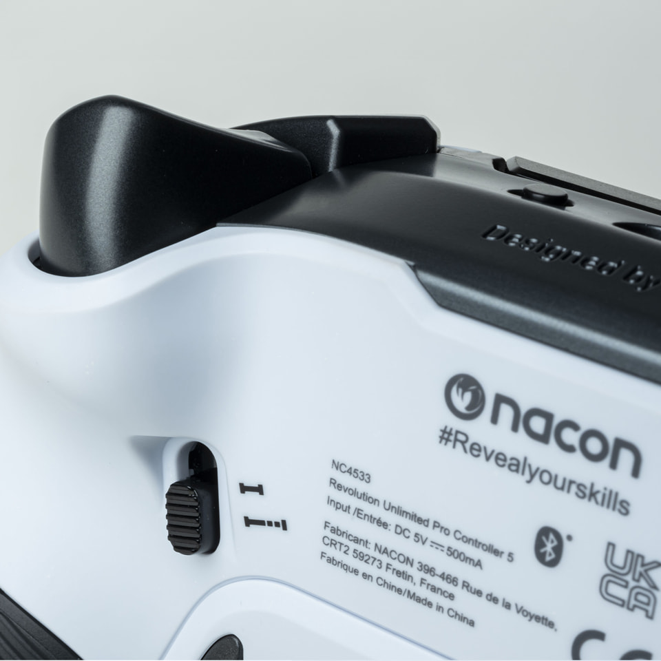 Nahaufnahme eines weißen und schwarzen Nacon-Controllers mit Text und Etiketten.