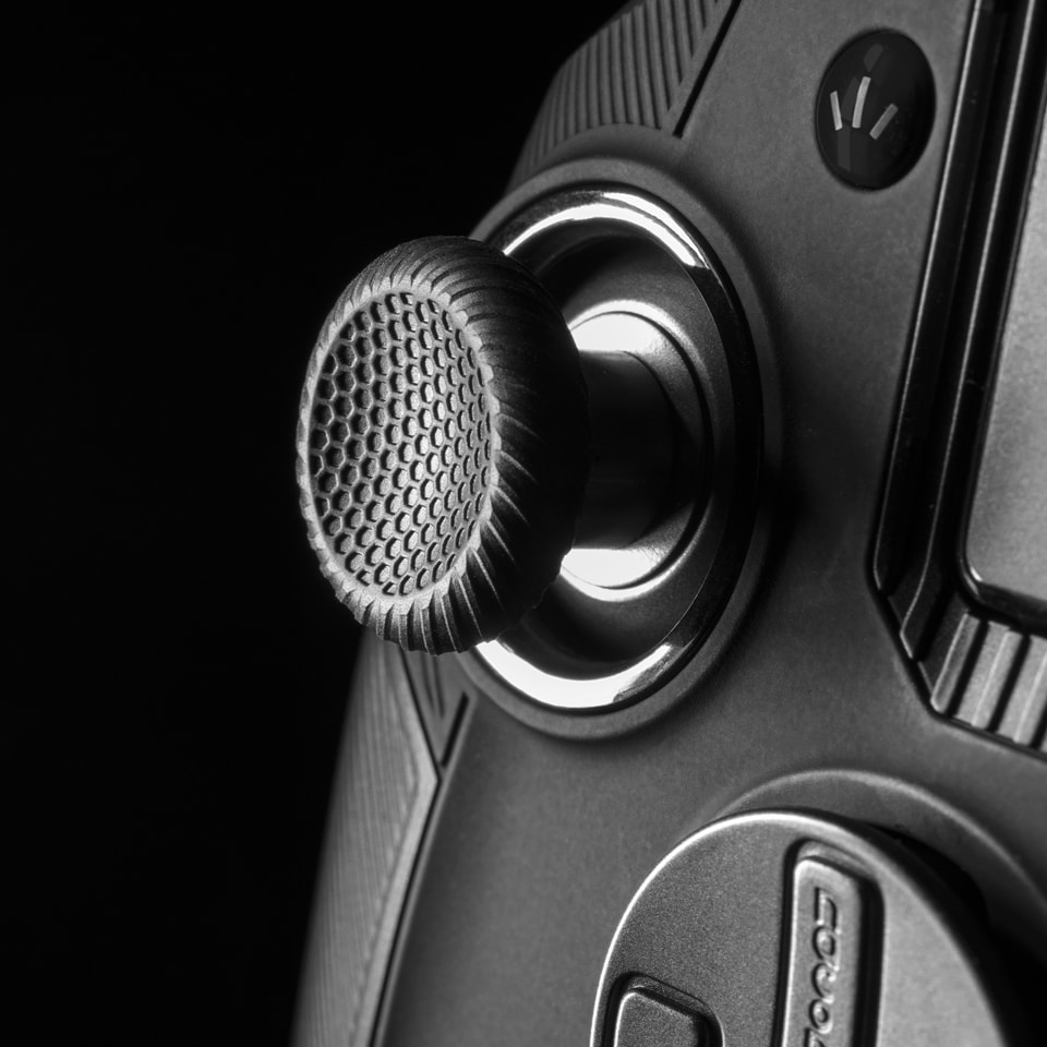 Nahaufnahme des Joysticks eines Gamecontrollers. Schwarzer Joystick mit strukturierter Oberfläche. Teil des Controllers sichtbar.