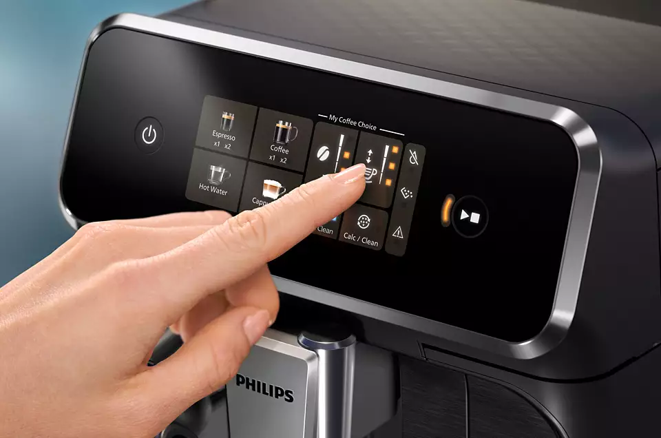 Primo piano dello schermo di una macchina da caffè. Una mano tocca lo schermo con più opzioni.
