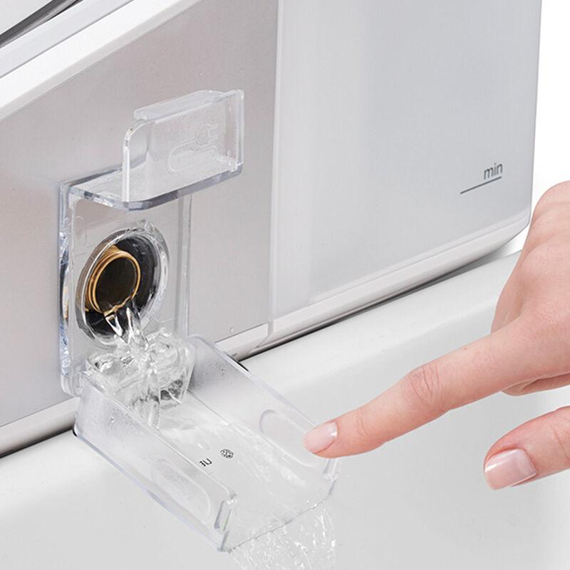 Een vinger wijst naar een wateruitlaat, water stroomt in een doorzichtige container.