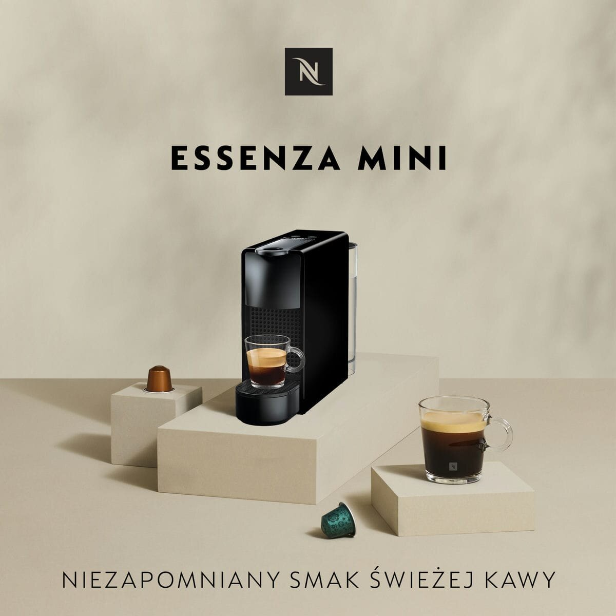 Czarny ekspres do kawy Nespresso Essenza Mini z kawą i kapsułkami.