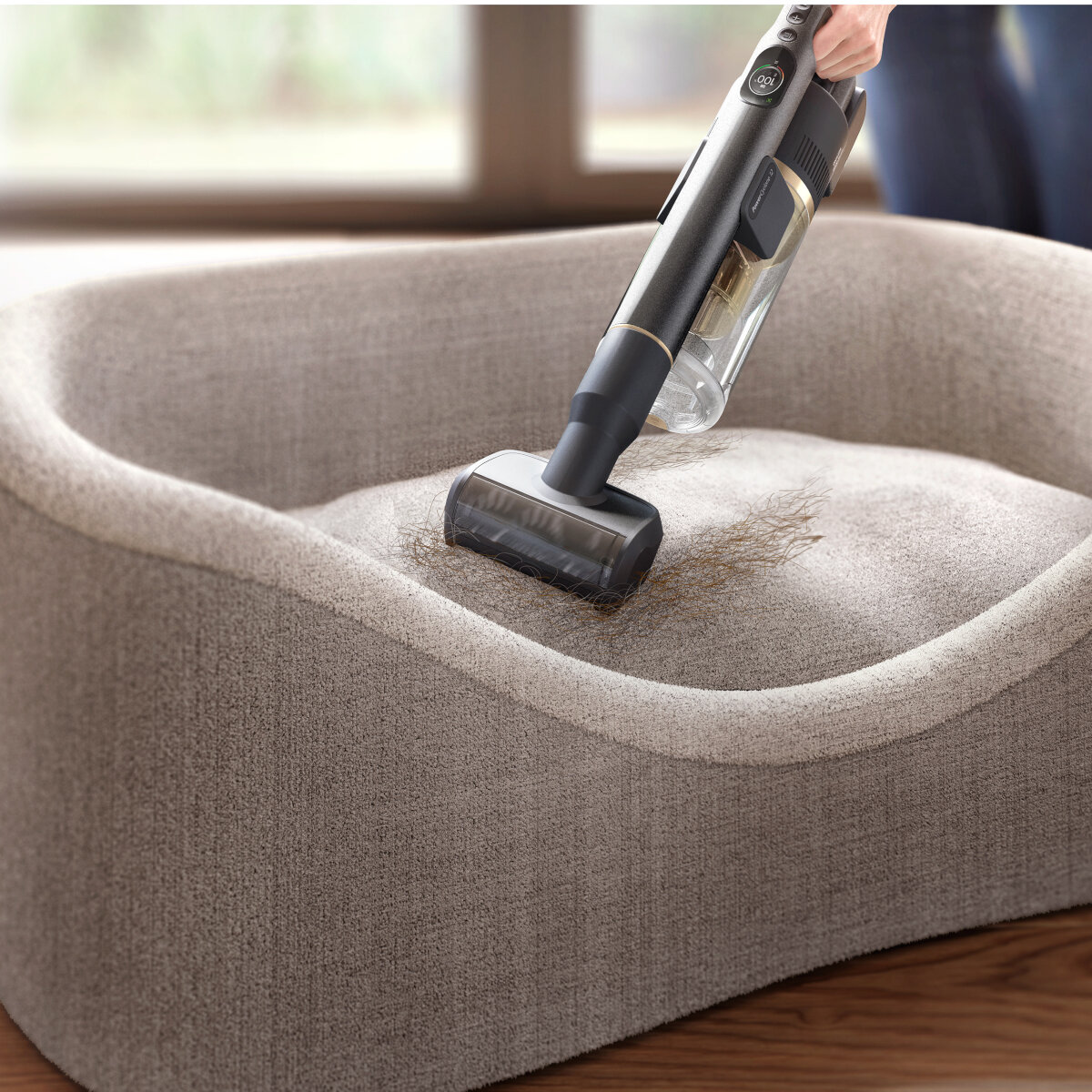 Ręczny odkurzacz odkurzający legowisko dla psa. Odkurzacz jest czarny i złoty.