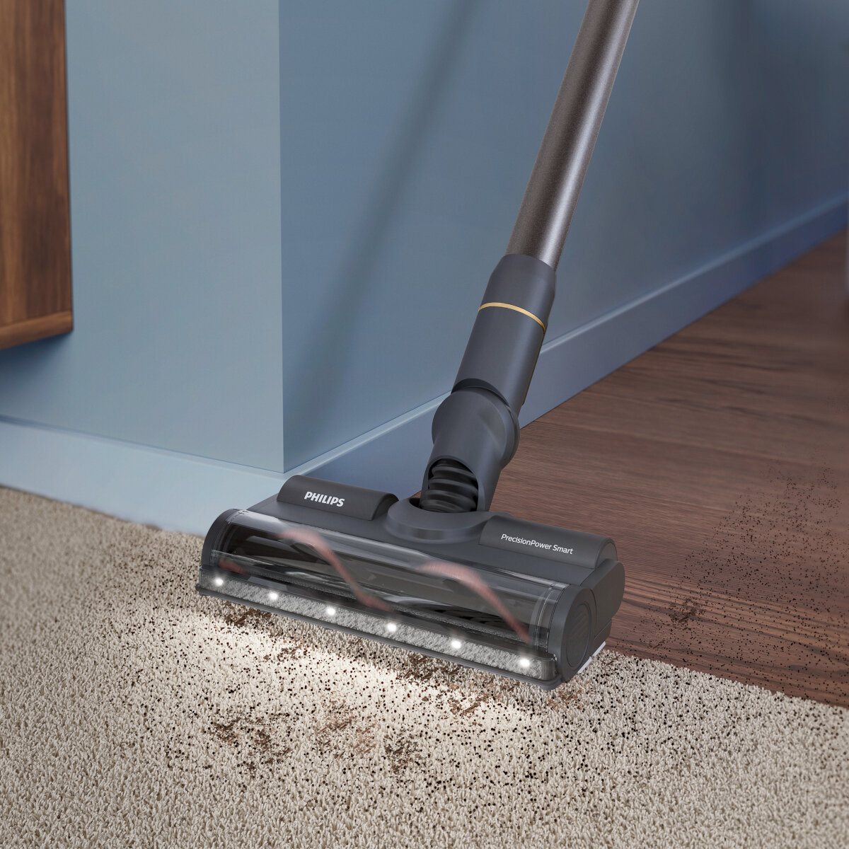 Głowica odkurzacza czyszcząca dywan, zbliżenie. Brązowy dywan i niebieska ściana.