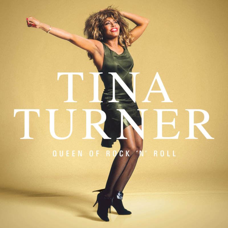 Tina Turner zöld ruhában, karokkal a levegőben pózol. Sárga háttér.