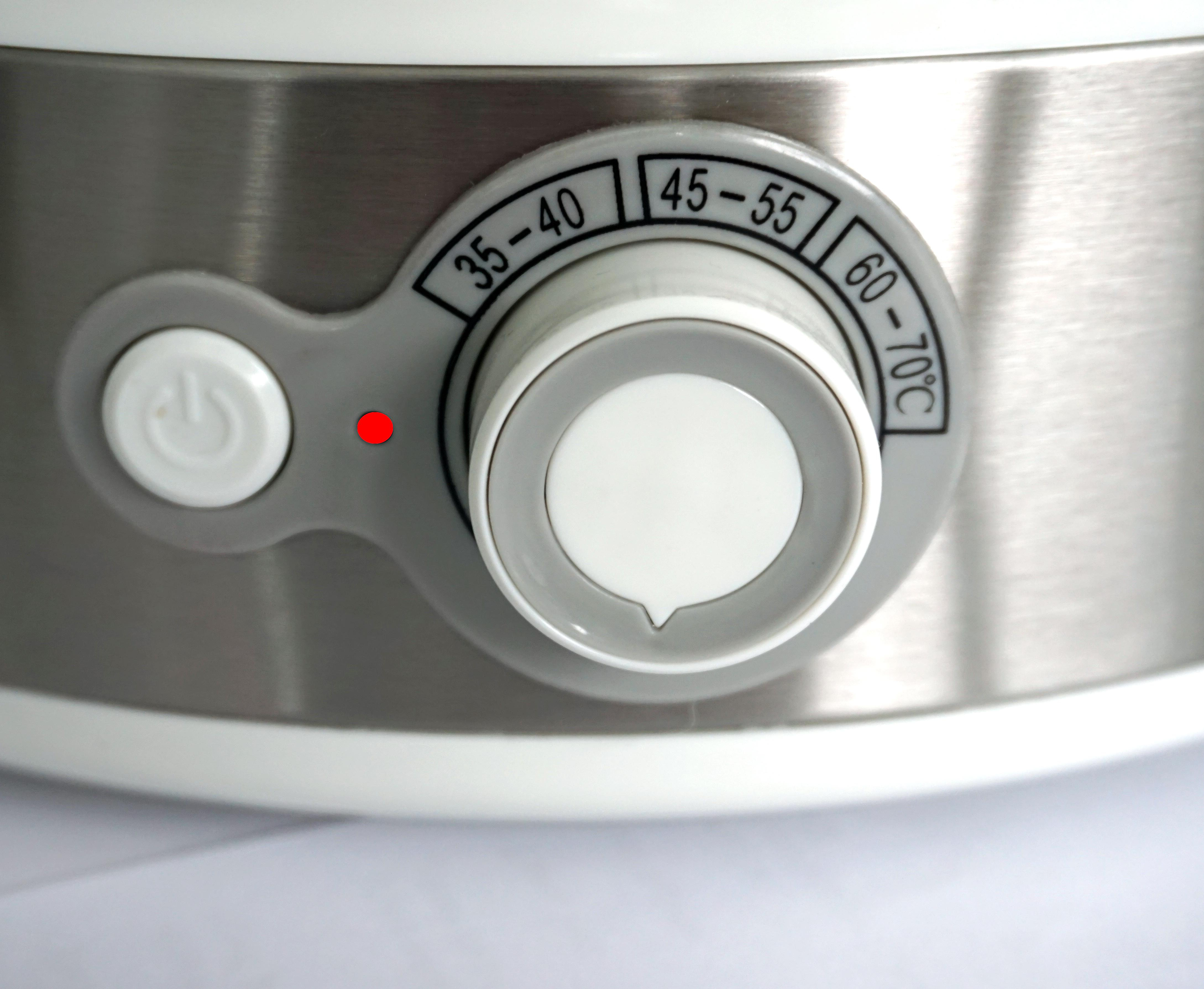 Nahaufnahme eines Bedienfelds mit Drehknopf und Licht auf einer weiß-grauen Maschine.