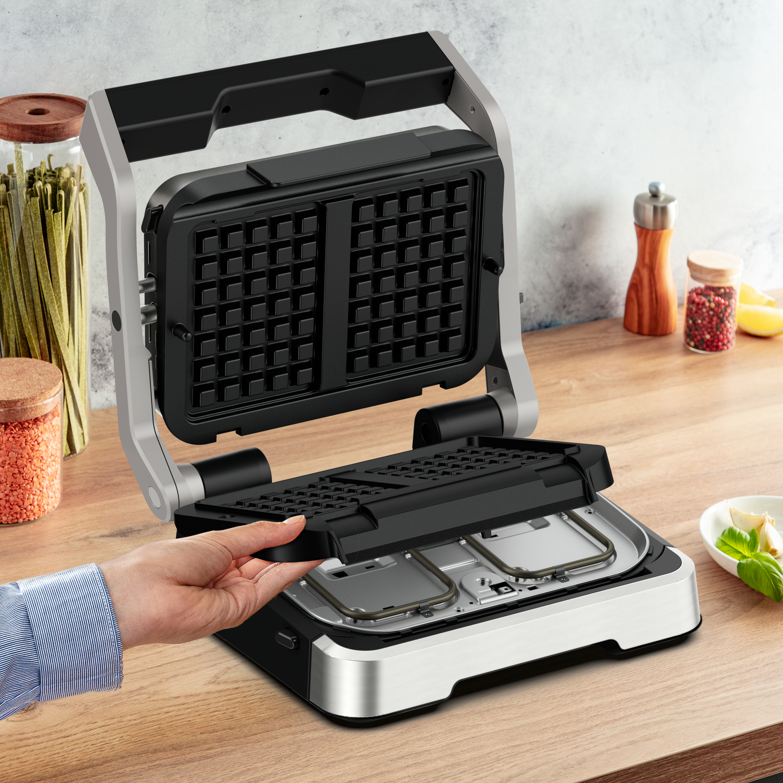 Eine Hand, die eine Waffeleisenplatte auf die Theke legt, mit Esswaren in der Nähe.