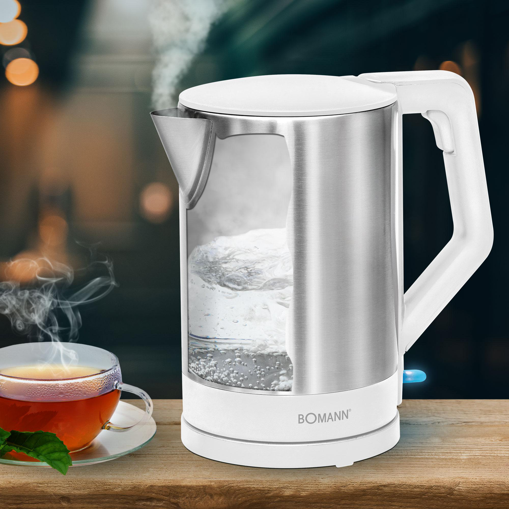 Ein silberner Wasserkocher kocht Wasser. Daneben eine Tasse Tee.