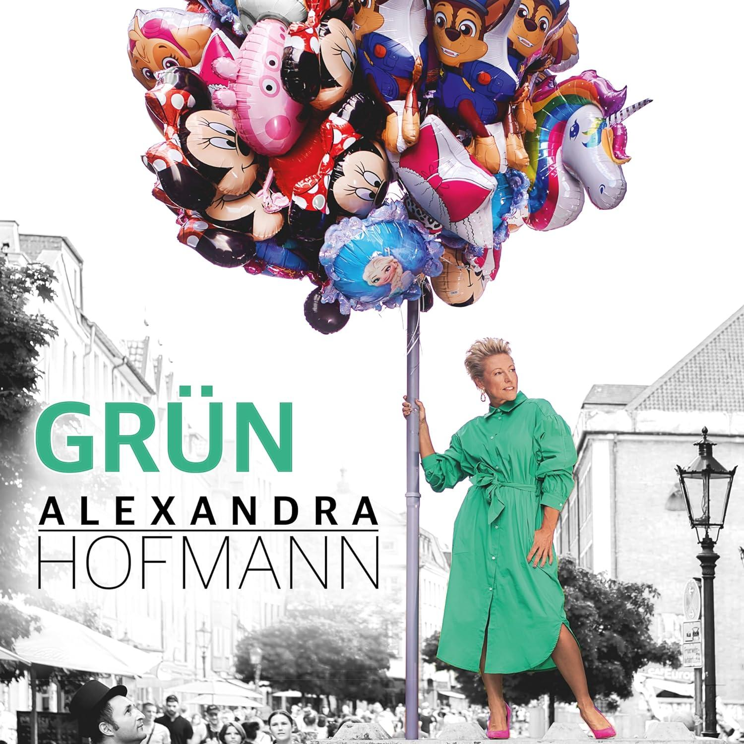 Frau in grünem Kleid mit Ballons. Text: Grün, Alexandra Hofmann. Gebäude im Hintergrund.