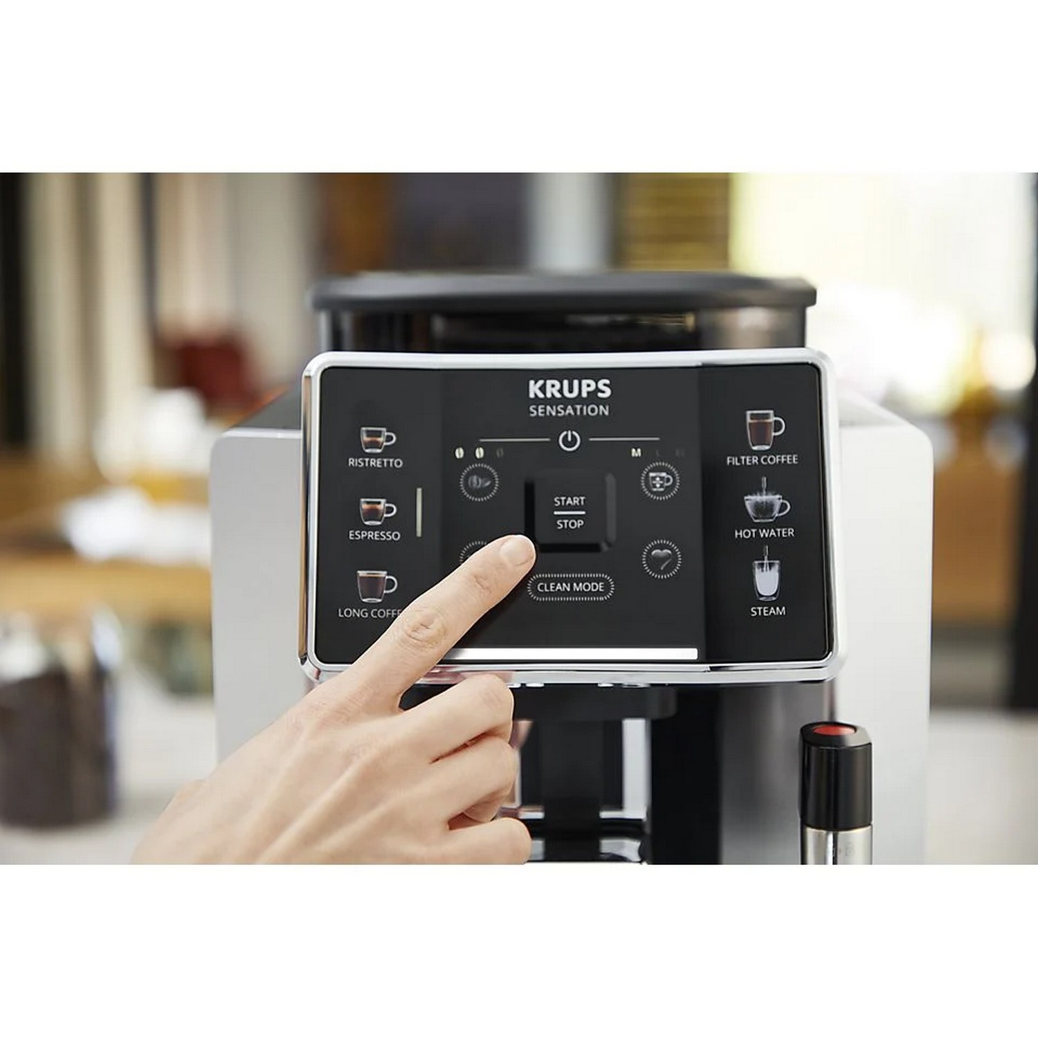 De hand van een persoon drukt op de 'start/stop'-knop van een Krups Sensations espressomachine.