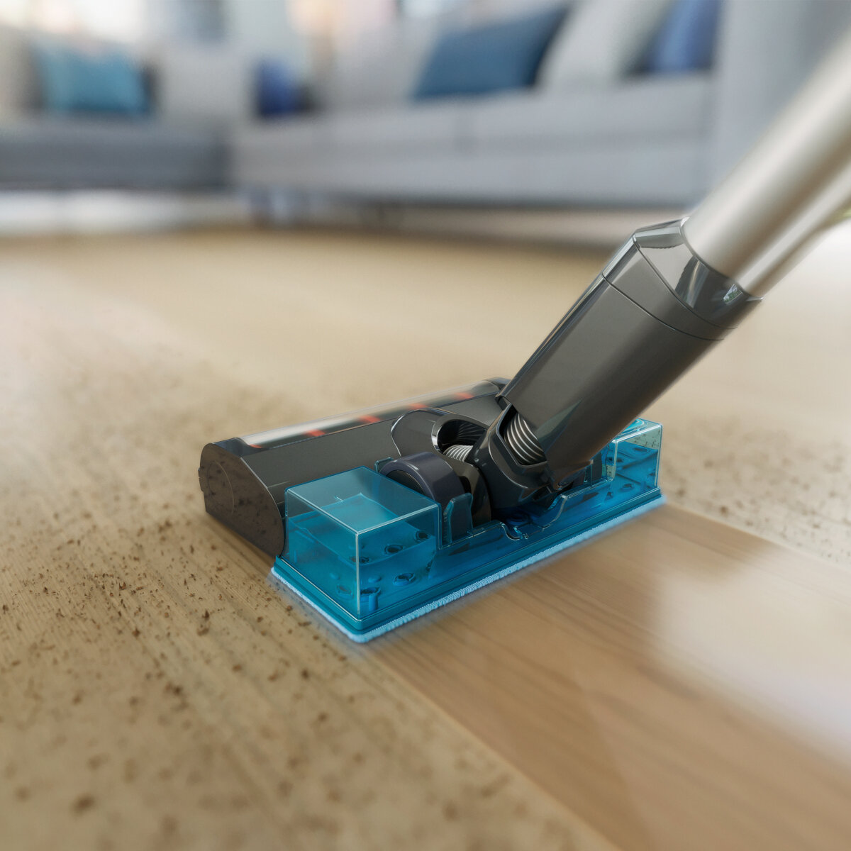 Zbliżenie głowicy odkurzacza czyszczącej podłogę z twardego drewna. Głowica jest niebieska.