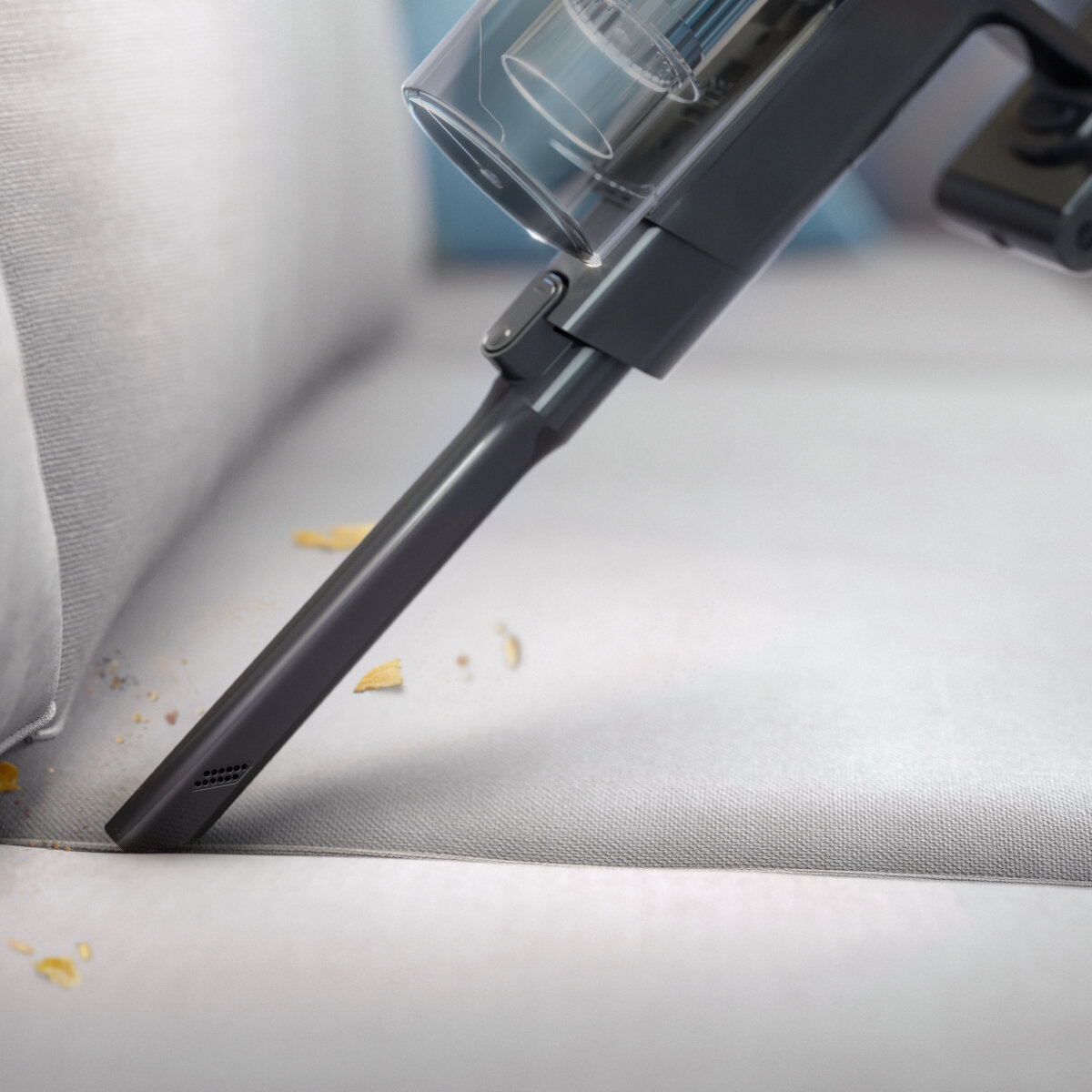 Szczegół dyszy odkurzacza czyszczącej jasnoszarą sofę.