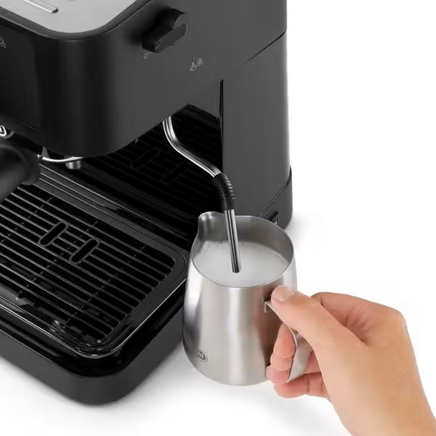 Hand die melk in een roestvrijstalen kan giet, naast een espressomachine.